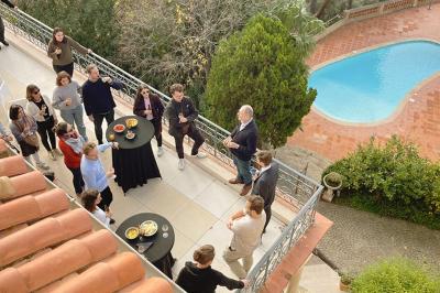 Vue d'une maison en pierre avec piscine, entourée de végétation, donnant sur une vallée et des collines sous un ciel bleu.