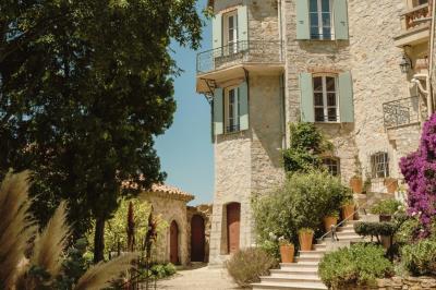 Vue d'une maison en pierre avec piscine, entourée de végétation, donnant sur une vallée et des collines sous un ciel bleu.