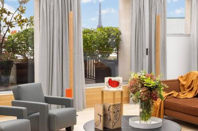 Salon lumineux avec canapé beige, table basse en bois, salle à manger attenante et escalier en arrière-plan.