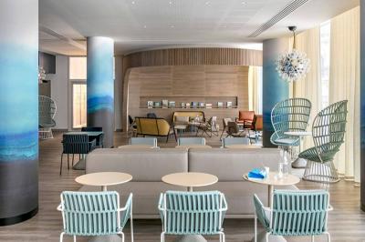 Espace lounge moderne avec fauteuils design, colonnes décorées de dégradés bleus et mobilier aux tons neutres.