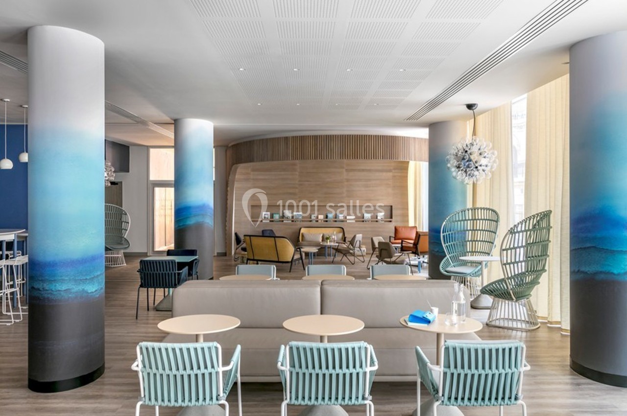 Espace lounge moderne avec fauteuils design, colonnes décorées de dégradés bleus et mobilier aux tons neutres.