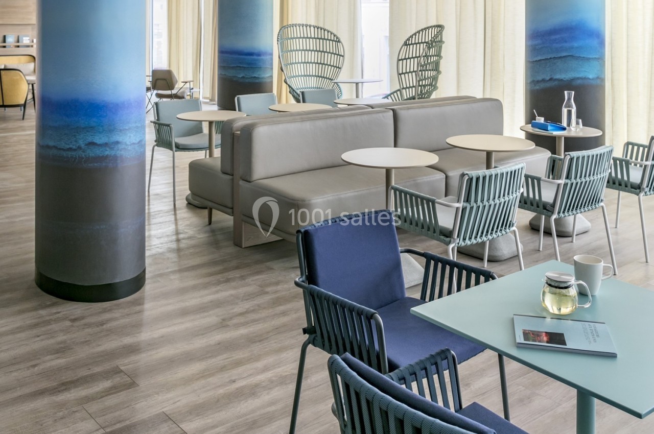 Espace lumineux avec des tables, chaises modernes et colonnes décorées, dans un cadre intérieur contemporain.