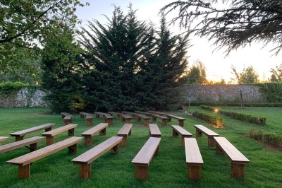 Salle de réunion lumineuse avec table en bois, chaises rembourrées, bouteilles d'eau et grandes fenêtres avec rideaux…