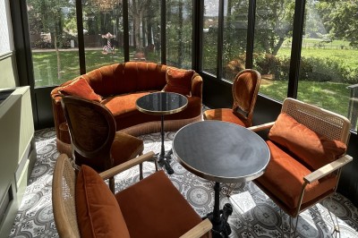 Salle de réunion lumineuse avec table en bois, chaises rembourrées, bouteilles d'eau et grandes fenêtres avec rideaux…