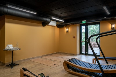 Salle de réunion lumineuse avec table en bois, chaises rembourrées, bouteilles d'eau et grandes fenêtres avec rideaux…