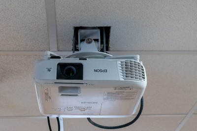 Façade d'un bâtiment commercial à deux étages avec parking et véhicules stationnés à l'avant.