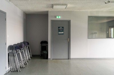 Façade d'un bâtiment commercial à deux étages avec parking et véhicules stationnés à l'avant.