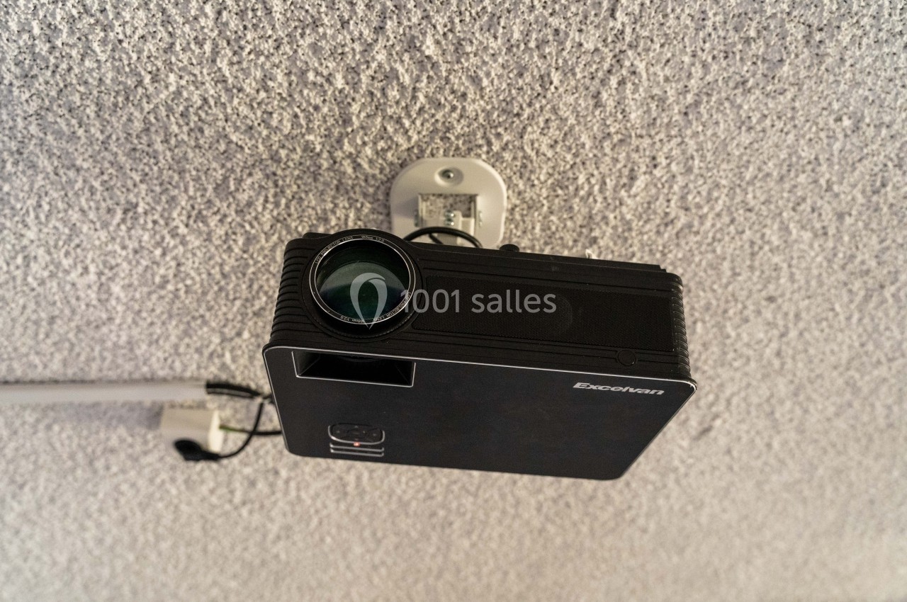 Projecteur noir fixé au plafond, orienté vers le bas, avec un câble d'alimentation visible.