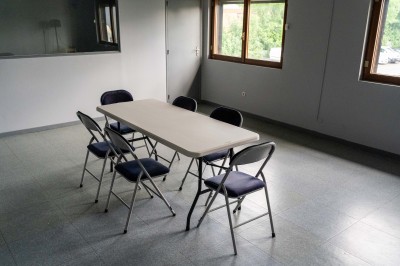 Façade d'un bâtiment commercial à deux étages avec parking et véhicules stationnés à l'avant.