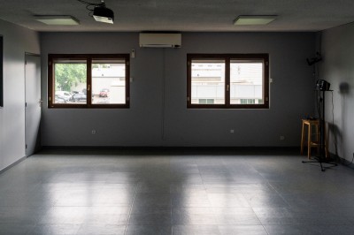 Façade d'un petit bâtiment commercial avec des places de parking et des véhicules stationnés à l'avant.