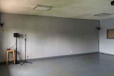 Façade d'un petit bâtiment commercial avec des places de parking et des véhicules stationnés à l'avant.