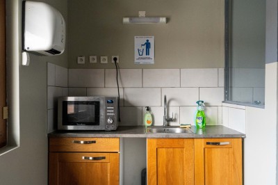 Façade d'un petit bâtiment commercial avec des places de parking et des véhicules stationnés à l'avant.