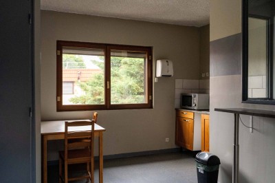 Façade d'un petit bâtiment commercial avec des places de parking et des véhicules stationnés à l'avant.