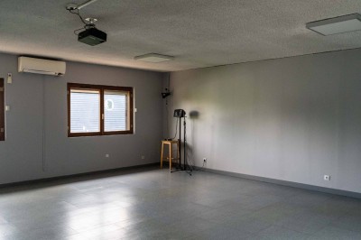 Façade d'un petit bâtiment commercial avec des places de parking et des véhicules stationnés à l'avant.