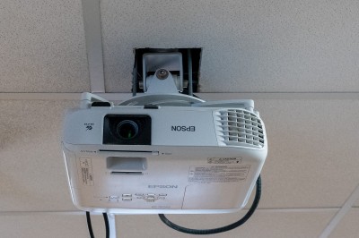 Façade d'un petit bâtiment commercial avec des places de parking et des véhicules stationnés à l'avant.