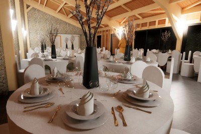Salle de réception élégante avec tables rondes dressées, nappes blanches et décorations florales dans un cadre lumineux en…