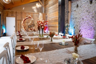 Salle de réception élégante avec tables rondes dressées, nappes blanches et décorations florales dans un cadre lumineux en…