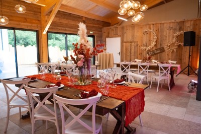 Salle de réception élégante avec tables rondes dressées, nappes blanches et décorations florales dans un cadre lumineux en…