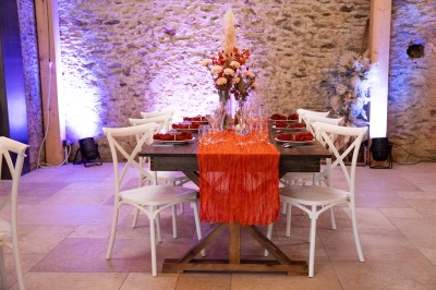 Salle de réception élégante avec tables rondes dressées, nappes blanches et décorations florales dans un cadre lumineux en…