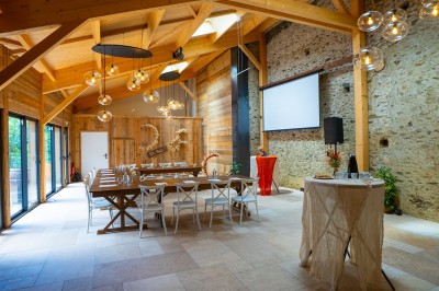 Salle de réception élégante avec tables rondes dressées, nappes blanches et décorations florales dans un cadre lumineux en…