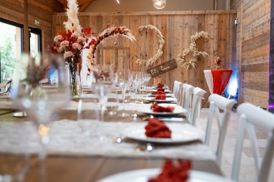 Salle de réception élégante avec tables rondes dressées, nappes blanches et décorations florales dans un cadre lumineux en…