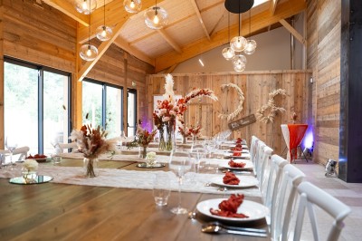 Salle de réception élégante avec tables rondes dressées, nappes blanches et décorations florales dans un cadre lumineux en…