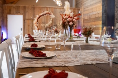 Salle de réception élégante avec tables rondes dressées, nappes blanches et décorations florales dans un cadre lumineux en…