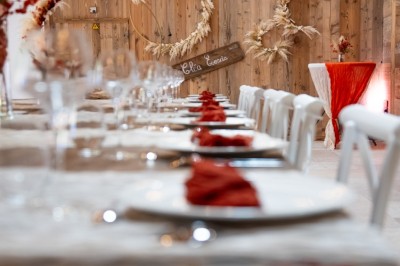 Salle de réception élégante avec tables rondes dressées, nappes blanches et décorations florales dans un cadre lumineux en…
