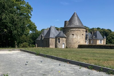 Cave voûtée en pierre avec tonneaux en bois, tabourets rustiques et escalier menant à l'extérieur.