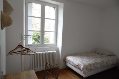 Cave voûtée en pierre avec tonneaux en bois, tabourets rustiques et escalier menant à l'extérieur.