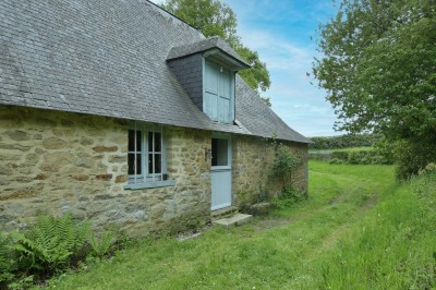 Cave voûtée en pierre avec tonneaux en bois, tabourets rustiques et escalier menant à l'extérieur.