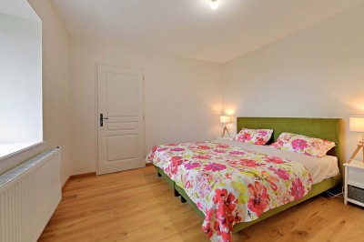 Cave voûtée en pierre avec tonneaux en bois, tabourets rustiques et escalier menant à l'extérieur.