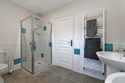 Cave voûtée en pierre avec tonneaux en bois, tabourets rustiques et escalier menant à l'extérieur.