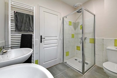 Cave voûtée en pierre avec tonneaux en bois, tabourets rustiques et escalier menant à l'extérieur.