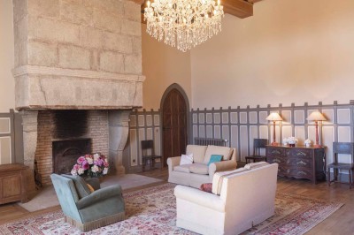 Cave voûtée en pierre avec tonneaux en bois, tabourets rustiques et escalier menant à l'extérieur.