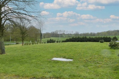 Cave voûtée en pierre avec tonneaux en bois, tabourets rustiques et escalier menant à l'extérieur.
