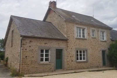Cave voûtée en pierre avec tonneaux en bois, tabourets rustiques et escalier menant à l'extérieur.