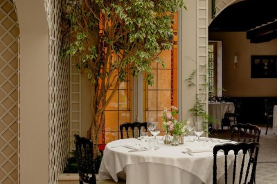 Bougie allumée sur un chandelier doré au centre d'une table dressée avec verres, fleurs et serviettes.