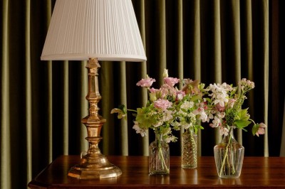 Bougie allumée sur un chandelier doré au centre d'une table dressée avec verres, fleurs et serviettes.