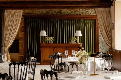Bougie allumée sur un chandelier doré au centre d'une table dressée avec verres, fleurs et serviettes.