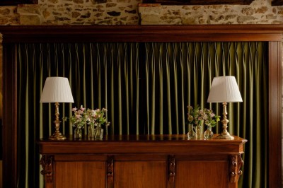 Bougie allumée sur un chandelier doré au centre d'une table dressée avec verres, fleurs et serviettes.