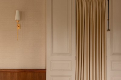 Salle de restaurant élégante avec tables dressées, chaises noires et décoration murale en treillis beige.
