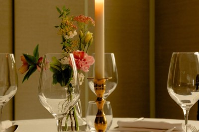 Salle de restaurant élégante avec tables dressées, chaises noires et décoration murale en treillis beige.