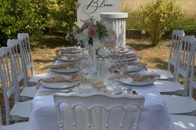 Table élégamment dressée avec nappes blanches, vaisselle raffinée, bougies roses et décoration florale assortie.