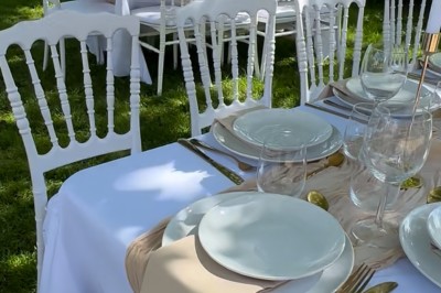 Table élégamment dressée avec nappes blanches, vaisselle raffinée, bougies roses et décoration florale assortie.