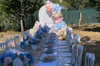 Table élégamment dressée avec nappes blanches, vaisselle raffinée, bougies roses et décoration florale assortie.