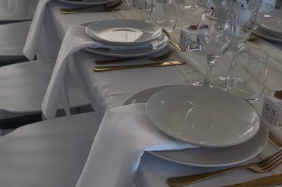 Table élégamment dressée avec nappes blanches, vaisselle raffinée, bougies roses et décoration florale assortie.