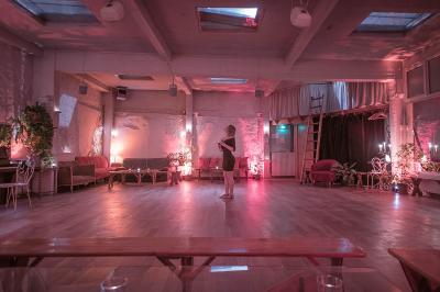 Salle spacieuse avec éclairage tamisé orange, murs en pierre, bancs en bois et décorations végétales.