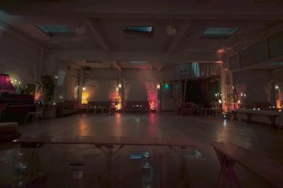 Salle spacieuse avec éclairage tamisé orange, murs en pierre, bancs en bois et décorations végétales.