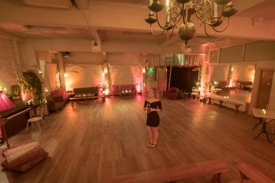 Salle spacieuse avec éclairage tamisé orange, murs en pierre, bancs en bois et décorations végétales.